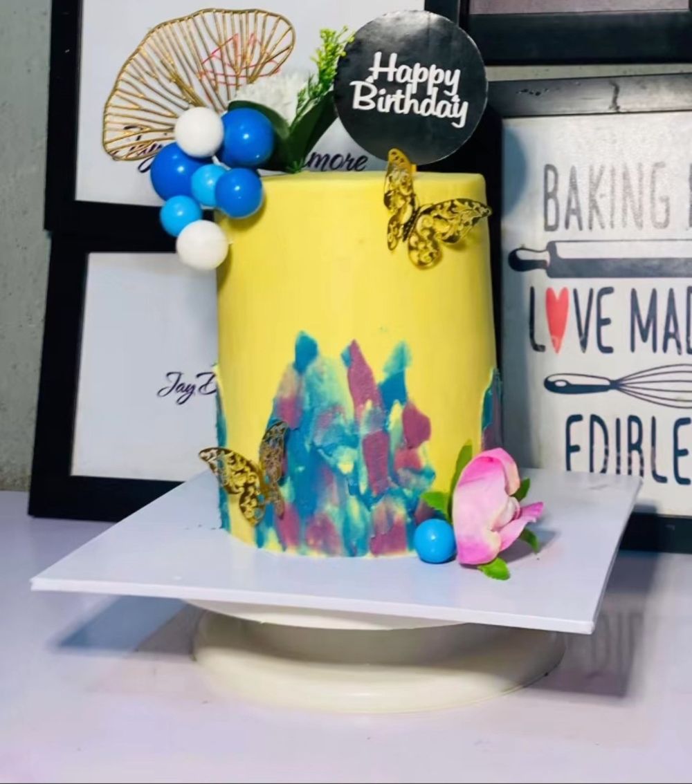 Yellow birthday cake with colourful brush strokes, gold butterflies and blue balls