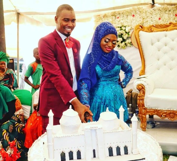 Bride and groom cutting a white mosque-shaped wedding cake